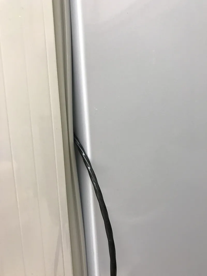Cable eléctrico que pasa a través del empaque de goma de la puerta de un refrigerador y deja una abertura